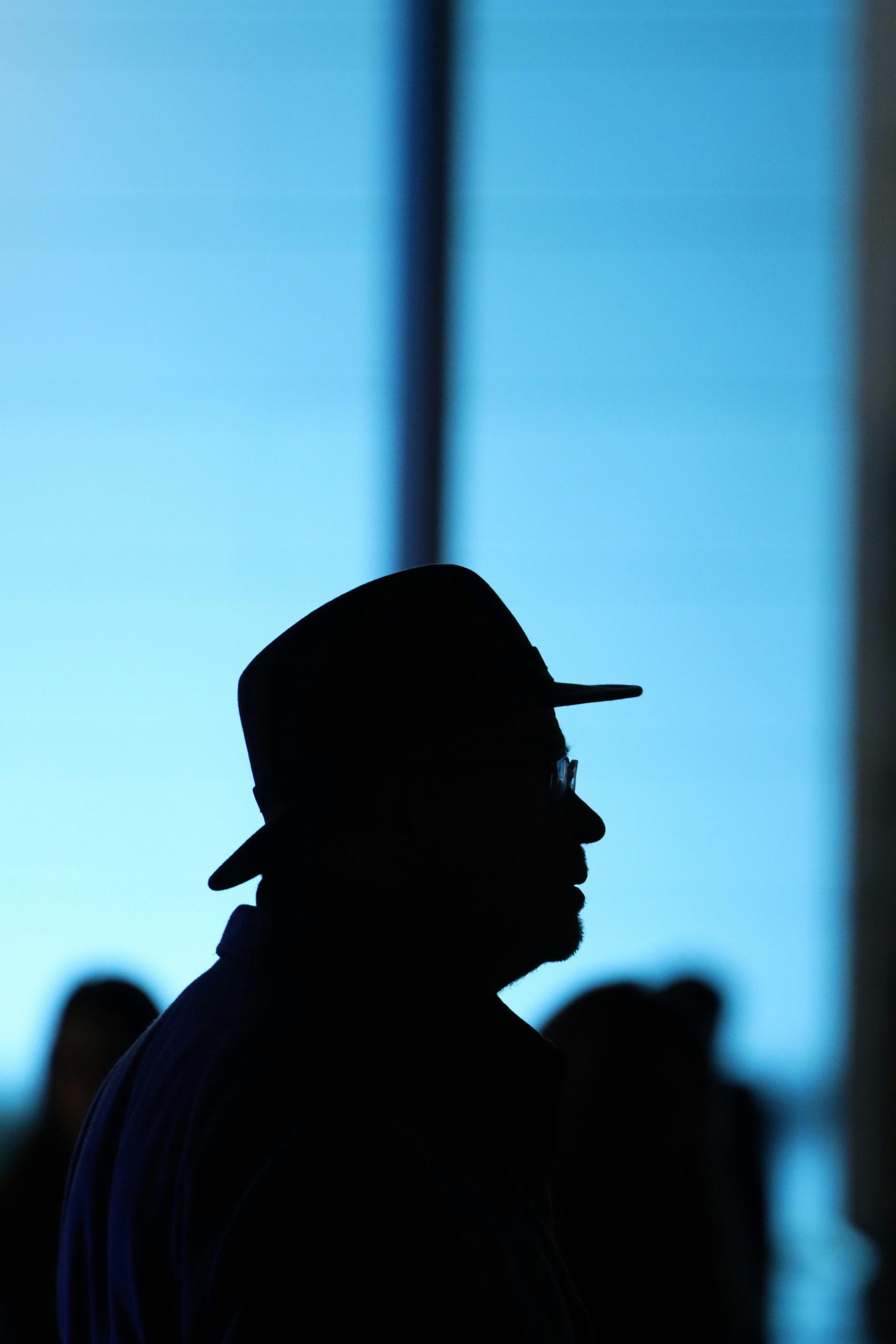 Silhouette of a person wearing a hat against a vibrant blue background, creating a dramatic nighttime scene.